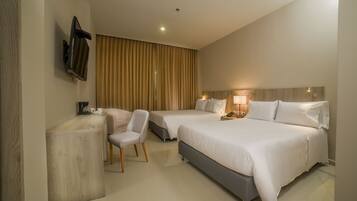 Quarto de hotel com duas camas, uma escrivaninha, uma cadeira, uma televisão e uma cortina.