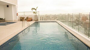 A rooftop swimming pool with clear blue water, surrounded by a glass railing, and overlooking a cityscape. - Hotel Dorado Plaza Alto Prado (Barranquilla)