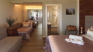 A hotel room with a large bed, a sofa, a small table with a vase, and a bathroom visible through an open door. - La Frescura del Principe (Agropoli)
