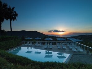 A poolside area with lounge chairs and umbrellas, overlooking a sunset over a mountainous landscape. - La Frescura del Principe (Agropoli)