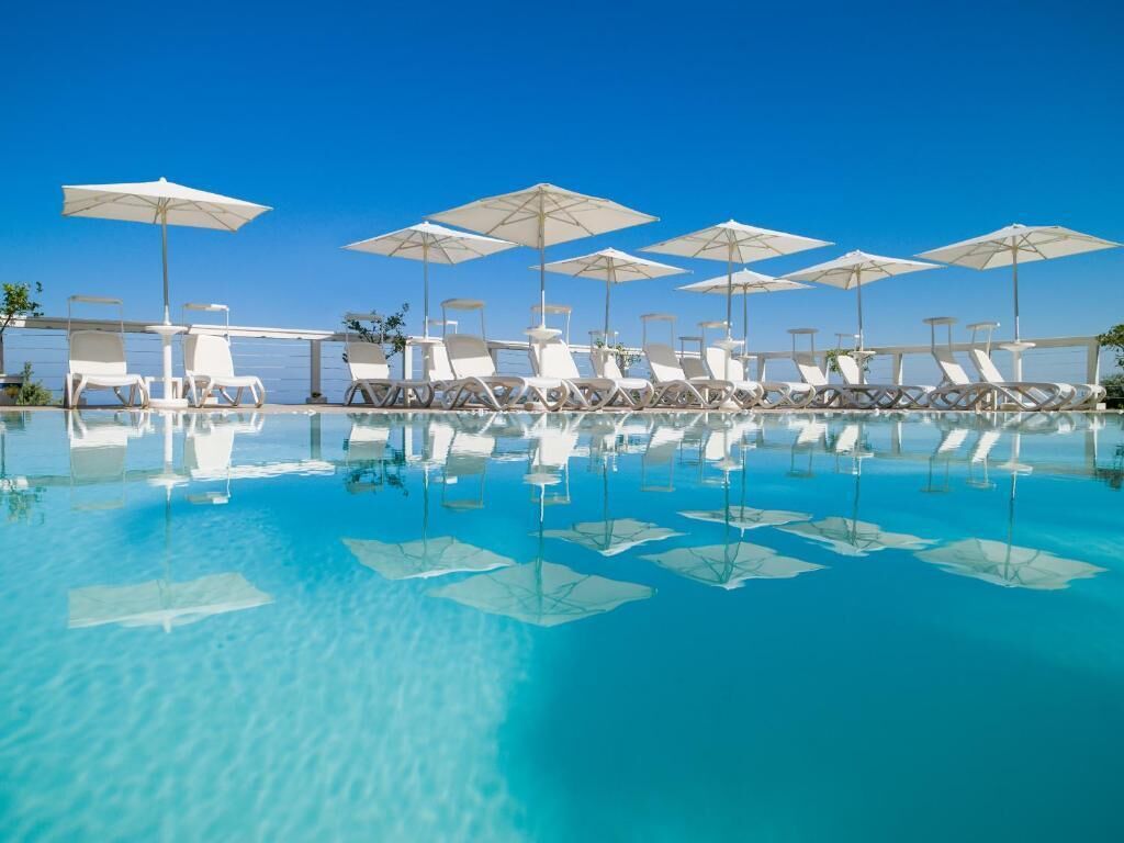 A pool area with lounge chairs and umbrellas.