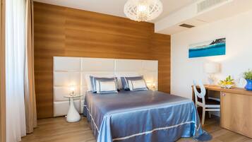 A modern bedroom with a large bed, bedside tables, a desk, and a painting on the wall.