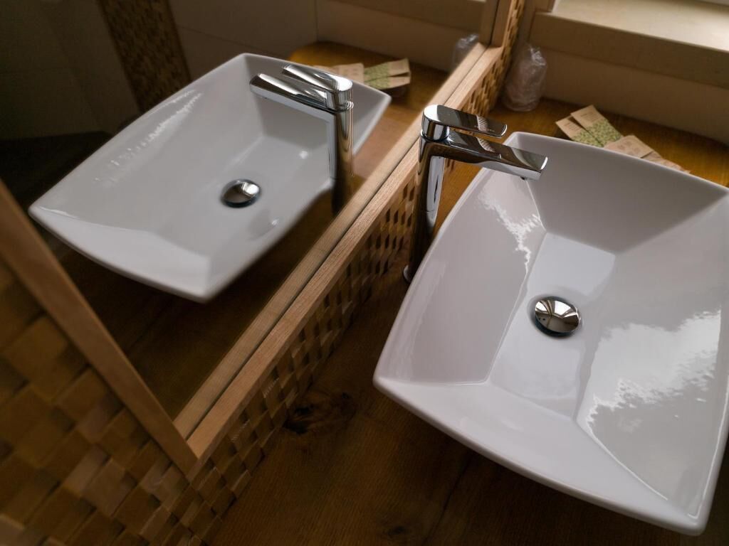 A bathroom with two white sinks, a chrome faucet, and a mirror above them.