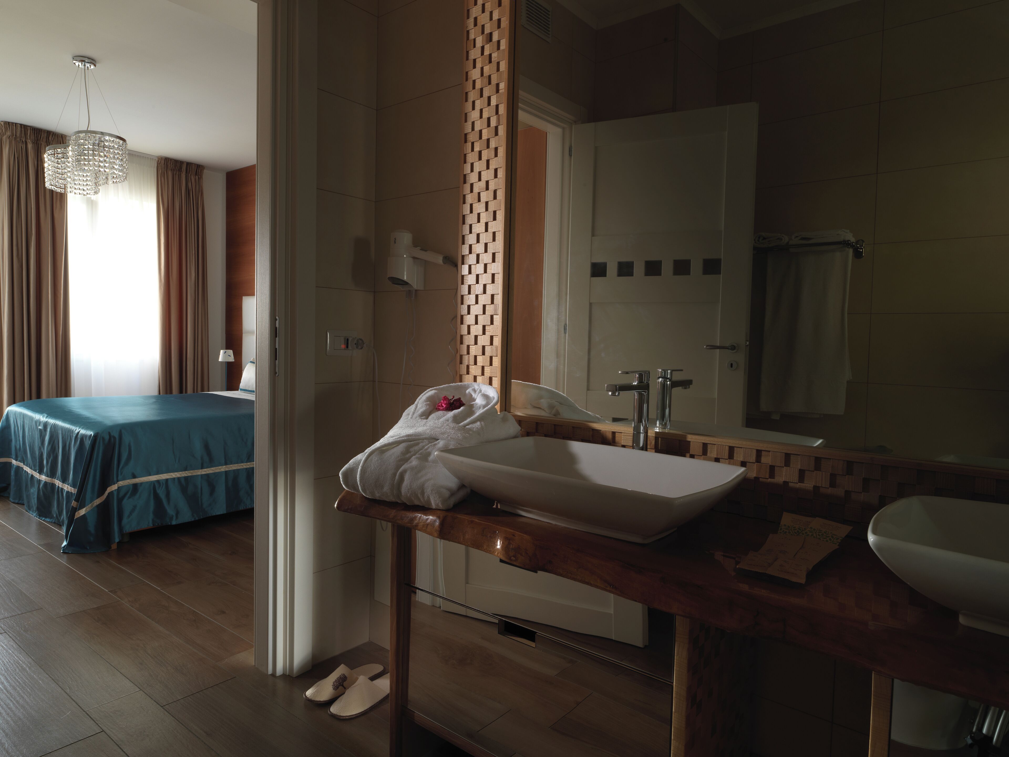 A hotel room with a bed, a bathroom with a sink and mirror, and a shower.