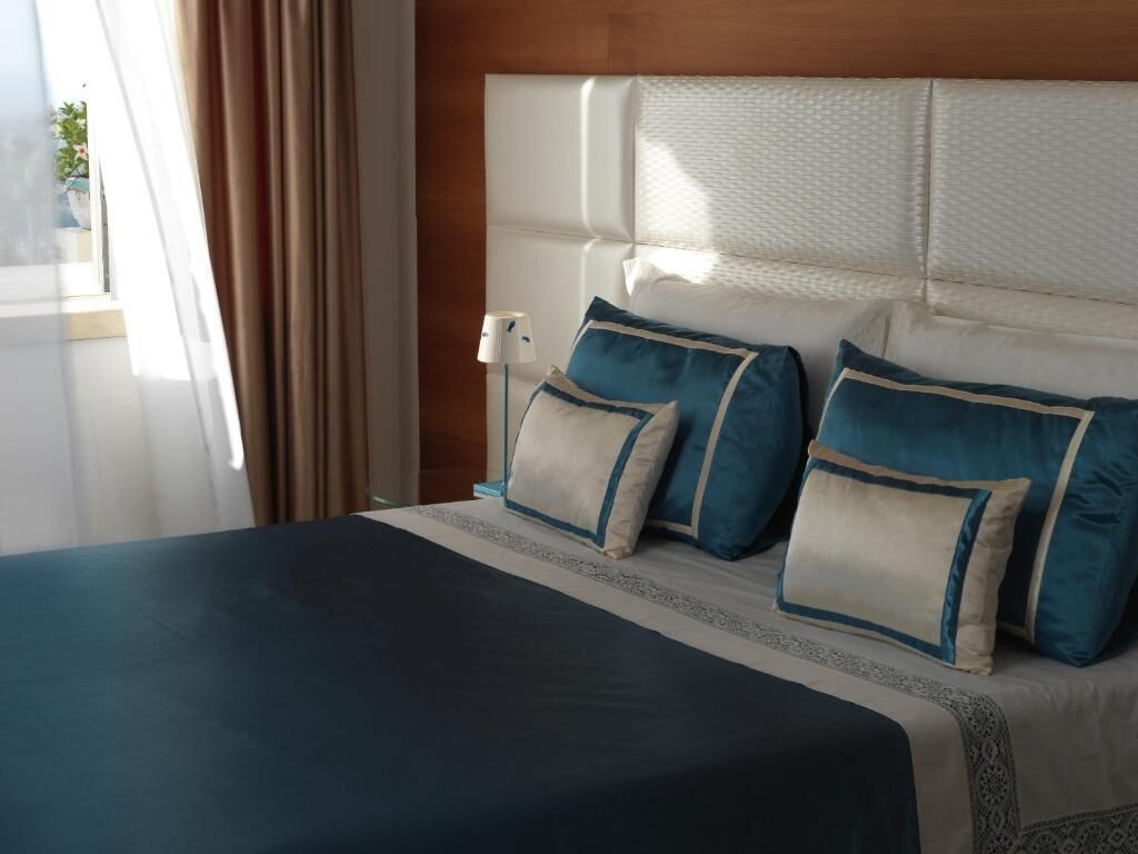 A hotel room with a large bed, a headboard, and a bedside lamp.