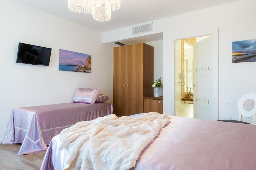 A bedroom with a bed, a bedside table, a wardrobe, and a television on the wall.