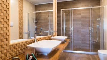 A modern bathroom with two sinks, a shower enclosure, and a wooden vanity.