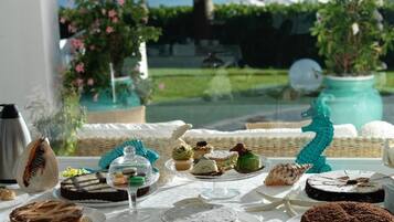 A table set with various desserts and pastries, a coffee pot, and a decorative teal sculpture.
