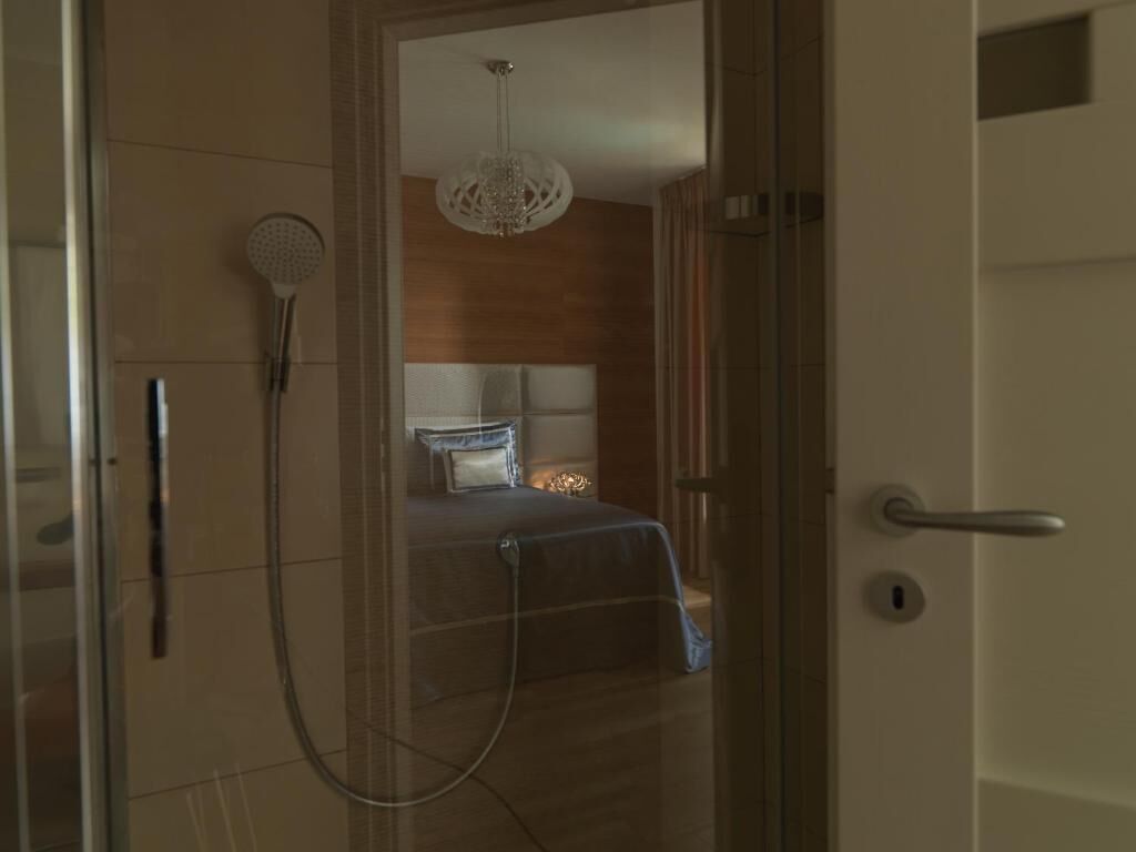 Ett hotellrum med dusch, säng och en kristallkrona.