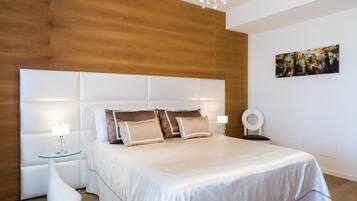 Un dormitorio moderno con una cama grande, dos mesitas de noche, una araña y un cuadro en la pared.