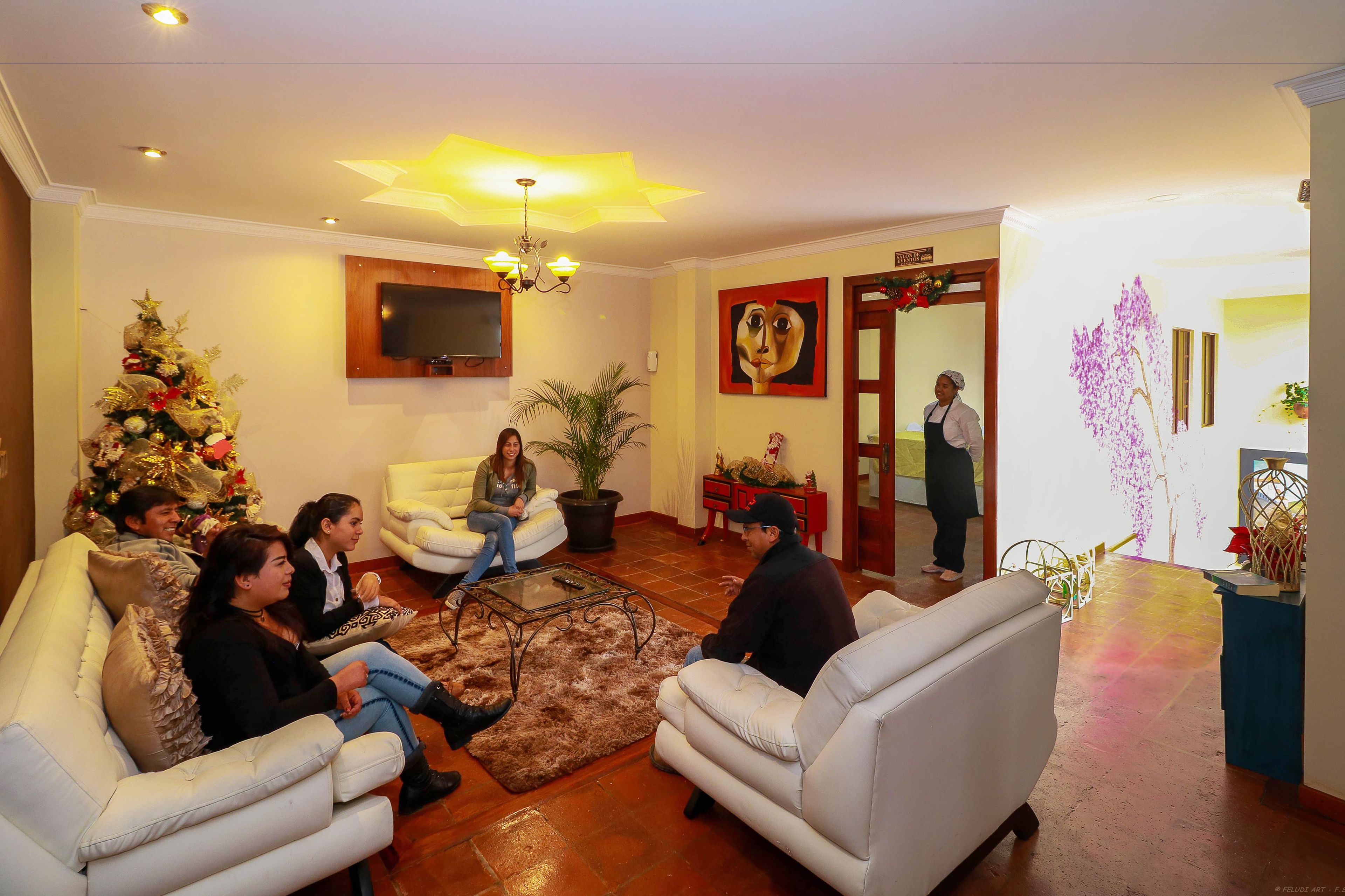 Un salon avec un sapin de Noël, des canapés, une table basse et un téléviseur fixé au mur.