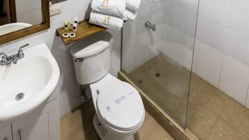 Un baño con inodoro, lavamanos, ducha y espejo.