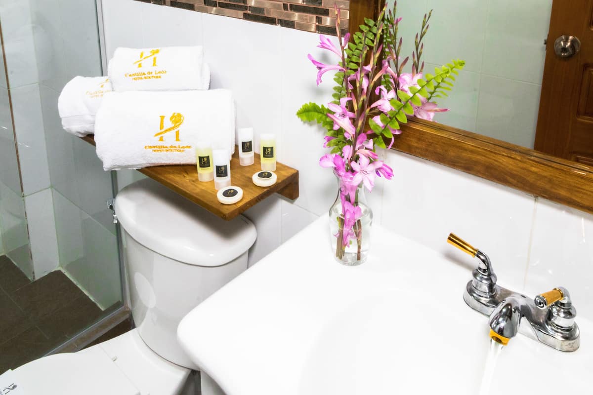 Un baño con inodoro, lavabo y ducha. Hay toallas y artículos de aseo en el inodoro.