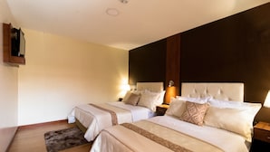 Habitación de hotel con dos camas, piso de madera y una pared decorativa oscura.