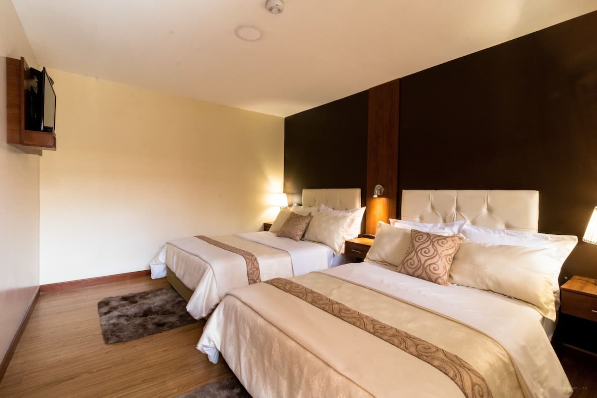 Habitación de hotel con dos camas, piso de madera y una pared decorativa oscura.