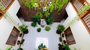 Un amplio atrio con techo alto, varias plantas en macetas y un candelabro central.