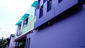 A modern building with a flat roof, large windows, and a small balcony. - Nap Corner Hostel (Phitsanulok)