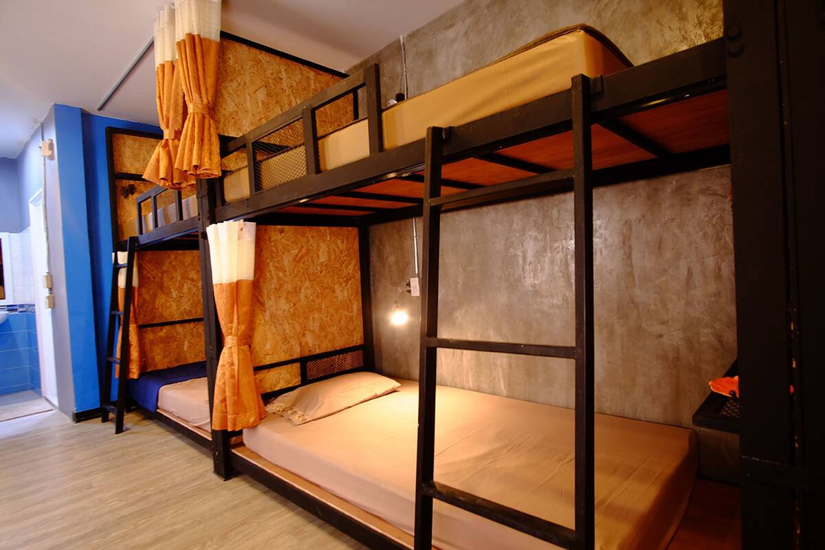 A bunk bed room with two beds, a ladder, and orange curtains.