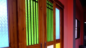 A hallway with wooden doors featuring green and white glass panels. - Nap Corner Hostel (Phitsanulok)