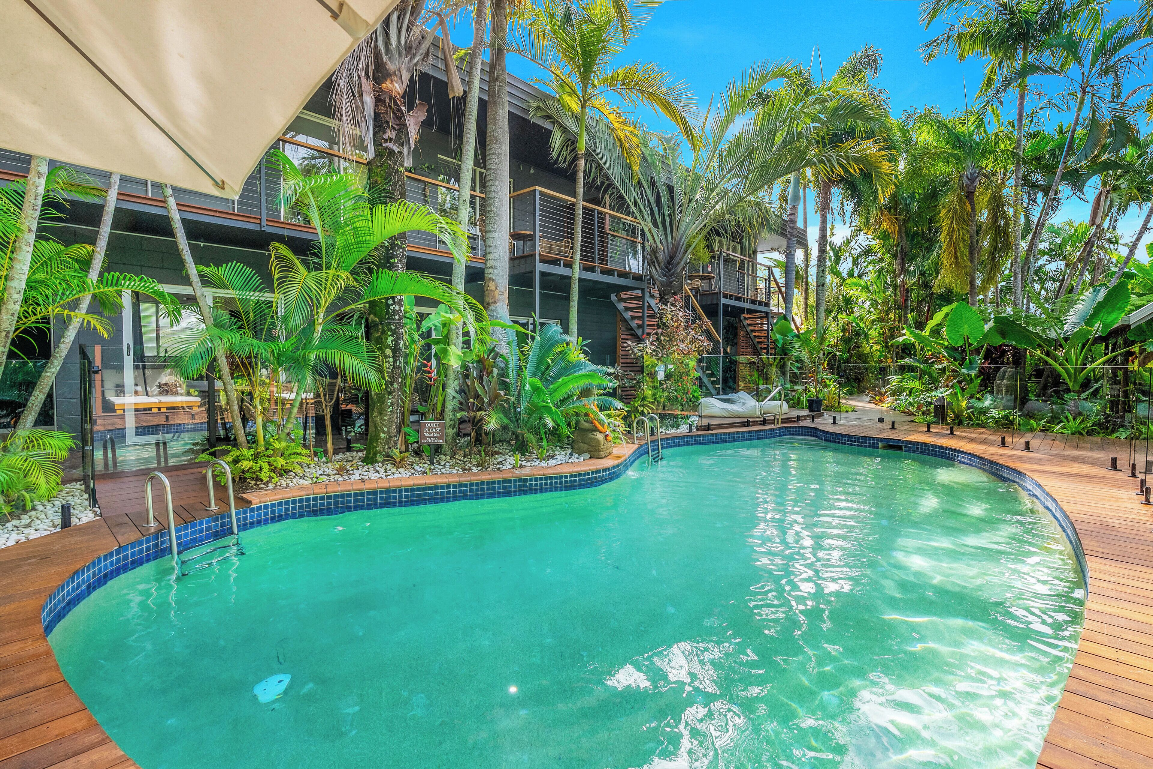 Una piscina rodeada de plantas tropicales y una terraza de madera.