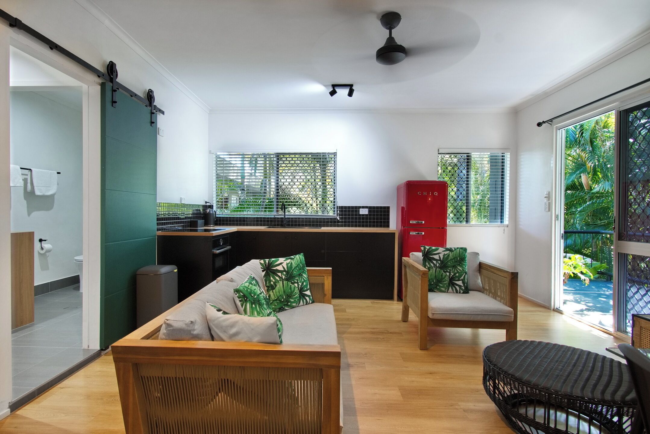 A modern living room with a sofa, chairs, and a dining area with a kitchen in the background.