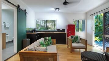 A modern living room with a sofa, chairs, and a dining area with a kitchen in the background.