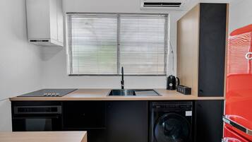 A compact kitchen with a sink, a dishwasher, a washing machine, and a red appliance.