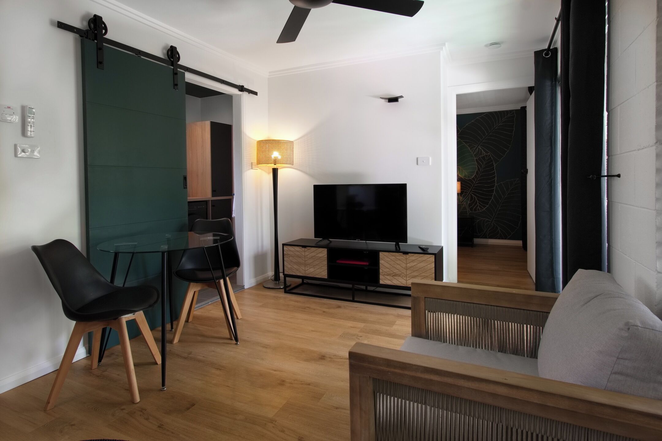 Una sala moderna con televisor, puerta corredera y comedor.