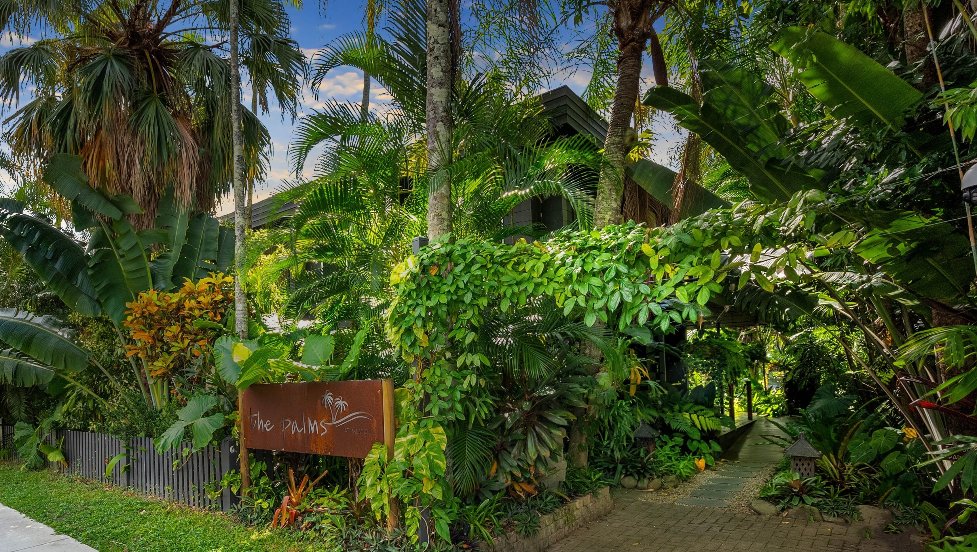 A lush garden with a sign reading "The Palms."