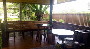 Um deck de madeira com um banco e uma mesa, uma torradeira e uma chaleira.