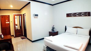 A hotel room with a bed, bedside table, nightstand, and a door leading to another room. - Khum Nakhon Hotel (Nakhon Si Thammarat)