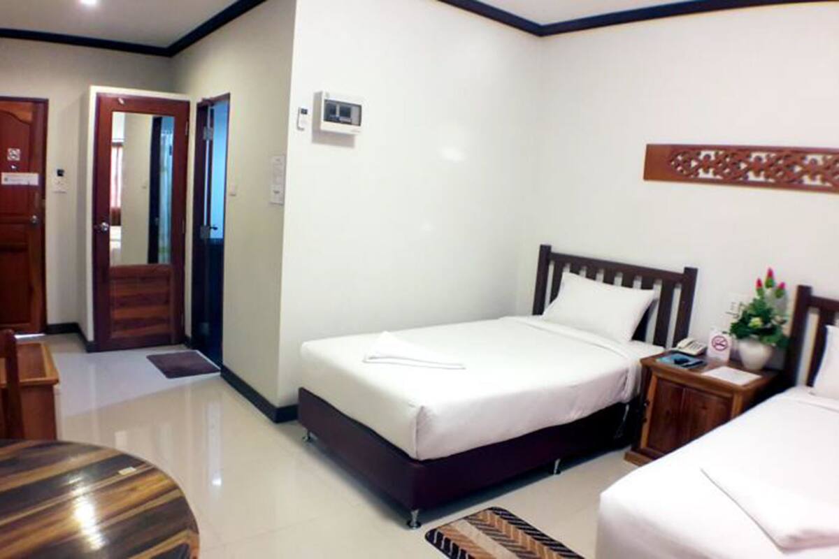 A hotel room with a bed, bedside table, and a small desk with a chair.
