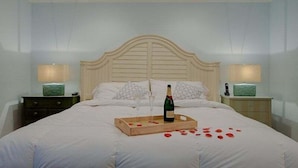 A neatly made bed with a wooden tray holding a bottle and glasses, and rose petals scattered on the bed. - Summertime - Direct River and Gulf Access (Fort Myers)