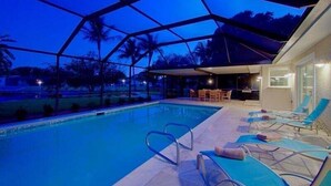 A swimming pool with lounge chairs and a covered seating area. - Summertime - Direct River and Gulf Access (Fort Myers)