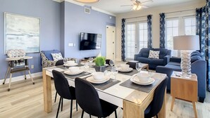 Un salon moderne comprenant un coin repas, un ventilateur de plafond et un téléviseur à écran plat.