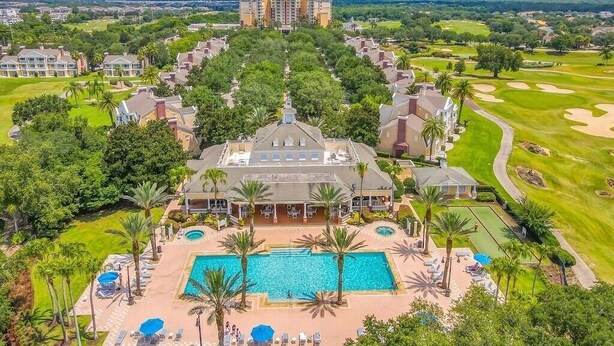Un complexe hôtelier doté d’une piscine centrale, de nombreuses chambres et d’un terrain de golf en arrière-plan.
