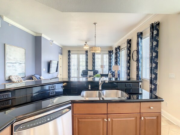 A modern kitchen with a black countertop, stainless steel appliances, and wooden cabinets.