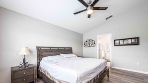 A bedroom with a bed, a nightstand, a ceiling fan, and a door leading to another room. - Premier Host-Beautiful 4BR/2BA Pool HEAT Home SAFE QUIET Lot - Disney 15 Minutes (Kissimmee)