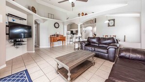 A spacious living area with a ceiling fan, a flat-screen TV, a leather sofa, and a wooden coffee table. - Premier Host-Beautiful 4BR/2BA Pool HEAT Home SAFE QUIET Lot - Disney 15 Minutes (Kissimmee)
