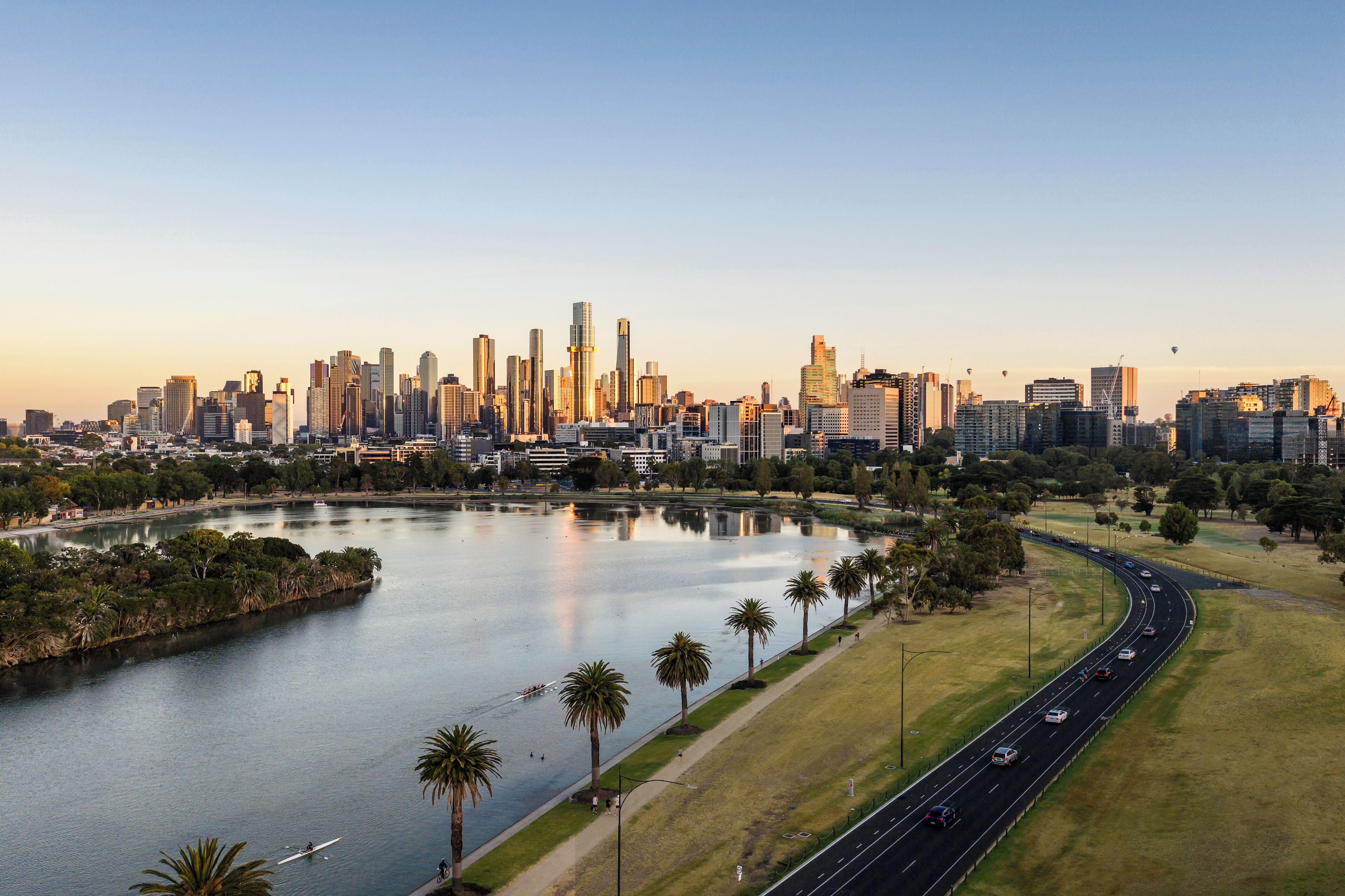 A city skyline with a river, palm trees, and a highway.