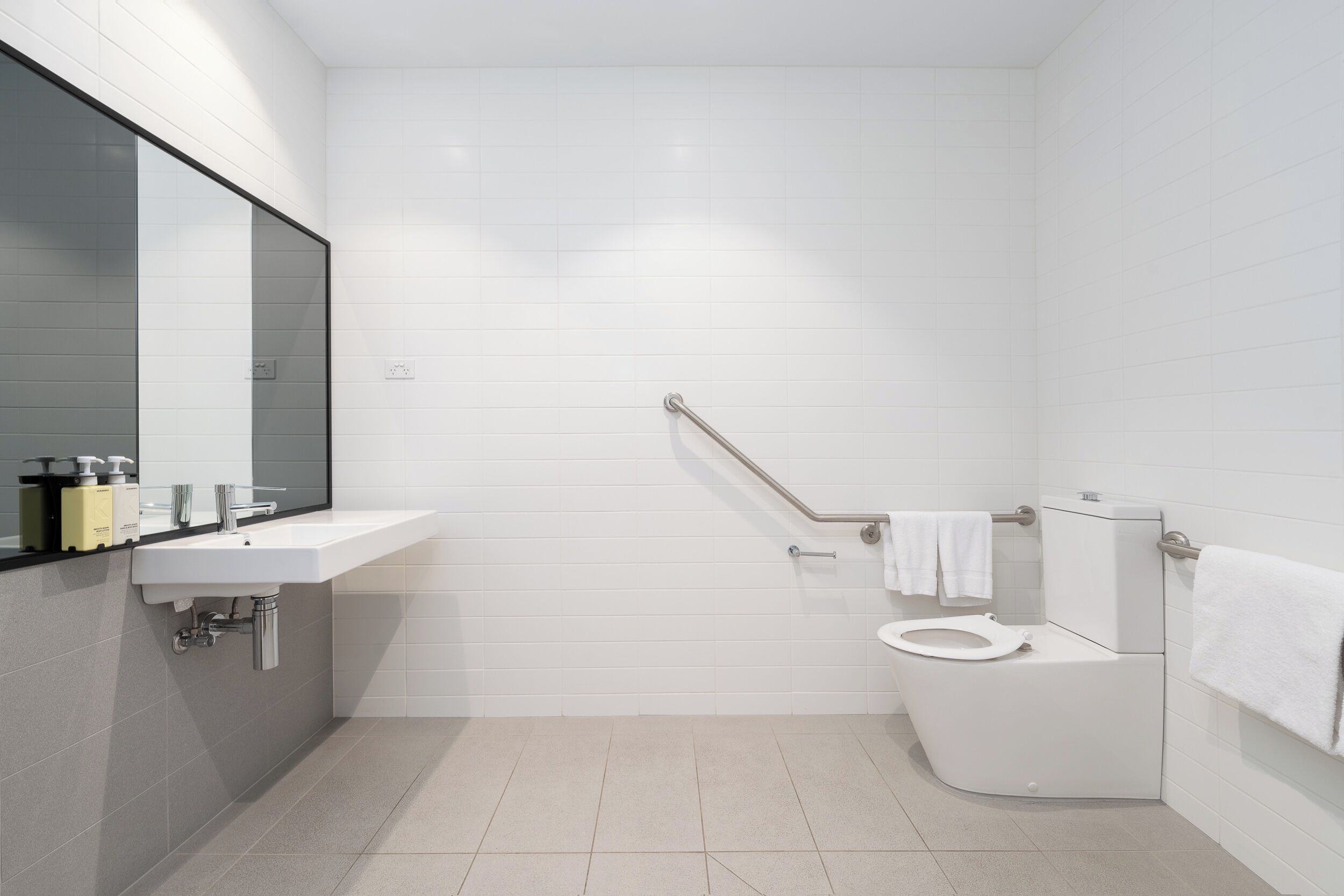 Ein modernes Badezimmer mit einem weißen Waschbecken, Spiegel und einer Toilette.