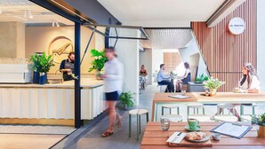 Un café moderne avec un comptoir, un espace salon et une enseigne indiquant « M. PERCIVAL ».
