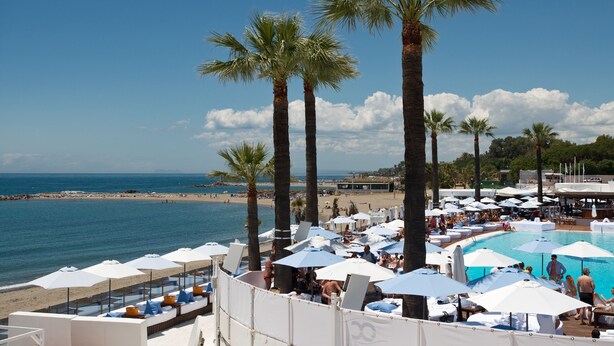 A beachside resort with palm trees, a pool, and beach umbrellas. - Beachside Puerto Banus Stunning Apartment 312 (Marbella)
