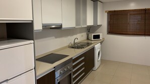 A compact kitchen with white cabinets, a microwave, a sink, a dishwasher, and a stove. - Sand House, New Apartment (Albufeira)