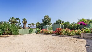 A fenced outdoor area with a gravel surface, surrounded by various plants and trees. - Kiltevna (Maslin Beach)