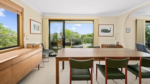 A conference room with a large wooden table, green upholstered chairs, a wooden cabinet, and a view of the outdoors through large windows. - Port of Call (Port Willunga)