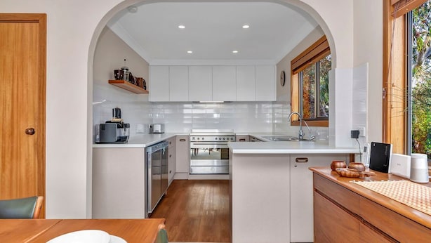A compact kitchen with white cabinets, a built-in oven, and a coffee machine. - Port of Call (Port Willunga)