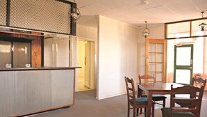 A dining area with a wooden table and chairs, a kitchen area with a counter and cabinets, and a door leading to another room.