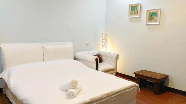 Une chambre d’hôtel avec un lit, une chaise, une petite table et deux tableaux encadrés au mur.