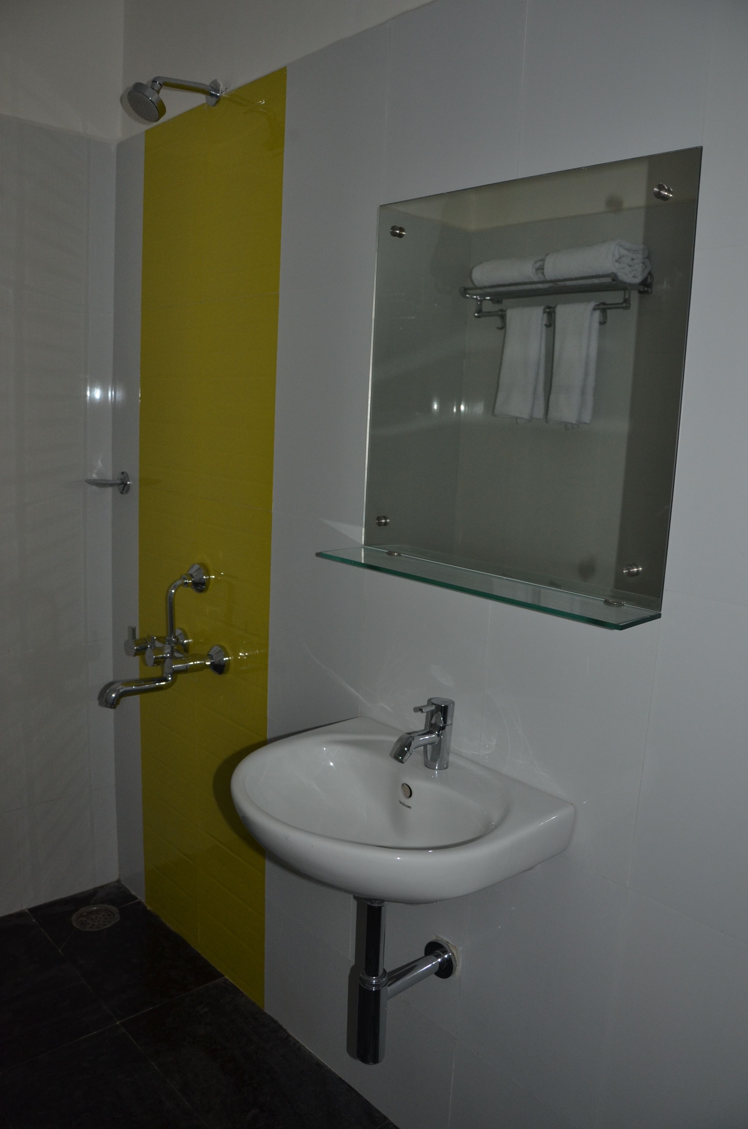 A bathroom with a white sink, a glass shelf above the sink, and a mirror.